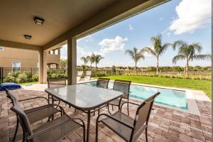 a patio with a table and chairs next to a swimming pool at Lovely Home With Theme Rooms, Game Room With Waterpark & Resort Access Resort Access At Encore Resort- 7705By in Kissimmee +22 photos