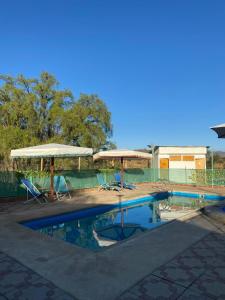 a swimming pool with two umbrellas and chairs at Hostal Panul in Panulcillo