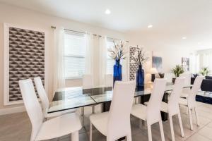 a dining room with a glass table and white chairs at Grand Home Near Disney With Private Pool, Media And Themed Rooms With Waterpark & Resort Access At Encore Resorts Reunion - 360Bu in Orlando +27 photos