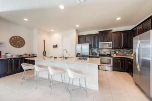 a kitchen with a large island with white stools at Grand Home Near Disney With Private Pool, Media And Themed Rooms With Waterpark & Resort Access At Encore Resorts Reunion - 360Bu in Orlando