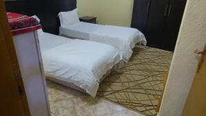 two beds with white sheets in a room at ناصر علي أبودهش للشقق المخدومة in Wadi Al Dawasir