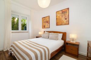 a white bedroom with a bed and two lamps at Garden Apartment with BBQ & Orange Tree - Near Lisbon & Sintra in Queluz