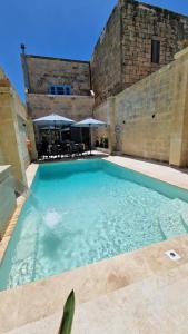 a large swimming pool in front of a building at Sunflower Farmhouse, Xewkija, Gozo in Xewkija