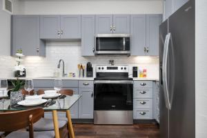 Una cocina con gabinetes blancos y un refrigerador de acero inoxidable. en 1BR Oasis w Pool&Parking, Near Rvrwlk & Conv Ctr, en San Antonio