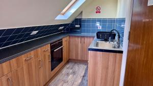 a kitchen with wooden cabinets and a sink at Large Modern Home Near Barking Station With SuperFast 1gbps Wi-Fi & Free Parking in Barking