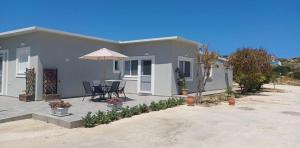 Casa con patio con mesa y sombrilla en Comfort Apartments, en Kefalos