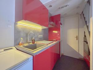 a kitchen with red cabinets and a sink at Charmante Maison, Terrasse,parking domaine du pins, piscine in Fréjus