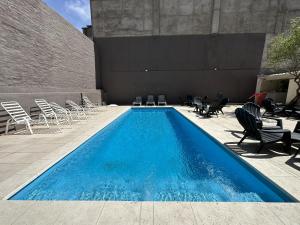 a swimming pool with chairs and a bunch of blue water at Ritz Hotel Mendoza in Mendoza