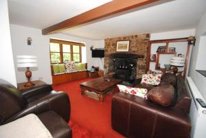 a living room with leather furniture and a fireplace at Exmoor Farmhouse in Bampton