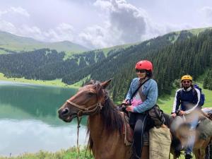 two people riding on horses next to a lake at Kordon guest house in Tar-Suu