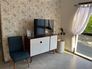 a living room with a tv on a cabinet and a chair at Reina Victoria in San Juan +7 photos