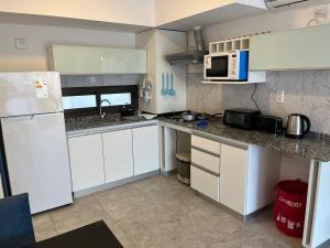 a kitchen with white cabinets and a white refrigerator at Reina Victoria in San Juan