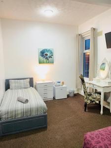 Un dormitorio con una cama, un escritorio y un espejo. en Aindale Hotel Blackpool, en Blackpool