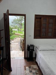 a bedroom with a bed and a door to a yard at Pousada Turmalina in Bueno Brandão