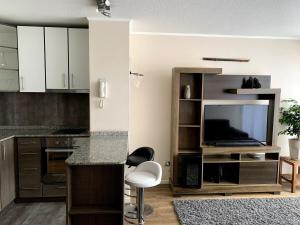 a kitchen with white cabinets and a tv and a counter at Relaxing apartment, exceptional location in Concepción