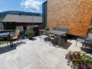 a patio with a table and chairs and flowers at Chalet & Almhostel Alpenperle - Selbstversorger Unterkunft in Tannheim