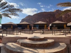 eine Gruppe von Gebäuden mit einem Berg im Hintergrund in der Unterkunft falling Stars Camp in Wadi Rum