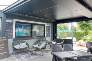 a patio with chairs and tables and windows at Camping Abijune d'Étretat in Le Tilleul