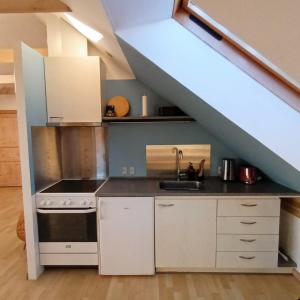 Eine Küche mit weißen Schränken und einem Spülbecken unter einer Treppe in der Unterkunft Hestegården in Fåborg + 8 Fotos