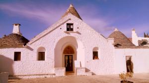 a large white building with a triangular roof at Miratrulli Apartment & Trullo dell'Aia in Alberobello