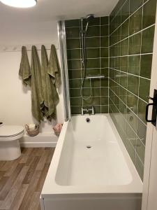 a bathroom with a tub and a toilet and green tiles at The Cottage in Sulgrave +89 photos