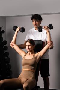 a man and a woman doing exercises with weights at Athenian Riviera Hotel& Suites in Athens