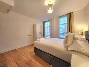 a large bedroom with a large bed and two windows at Spacious 2-Bed Flat - Close to Tube, Sleeps 6 in London