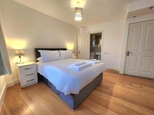 a bedroom with a large bed with white sheets and a night stand at Spacious 2-Bed Flat - Close to Tube, Sleeps 6 in London +12 photos