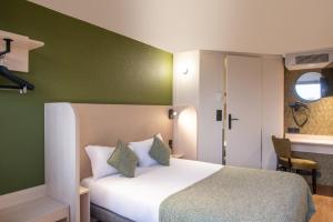 Un dormitorio con una cama y una pared verde. en Hôtel Olivet, Orléans Sud - Nouvelle Ouverture, en Olivet
