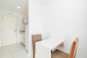 a white kitchen with a white table and chairs at Vision Hotel em Brasília 60613 in Brasilia