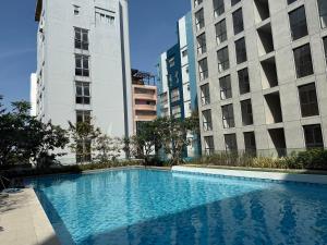 a swimming pool in the middle of two tall buildings at Regal 40 Srinakarin Apartment in Bangkok