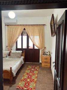 a bedroom with a bed and a window and a rug at Kështjella Myftari in Patos