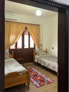 a bedroom with two beds and a rug on the floor at Kështjella Myftari in Patos