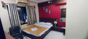 a small bedroom with a bed and a mirror at Arihant palace in Shirdi +6 photos