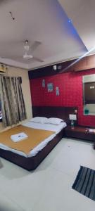 a bedroom with a large bed with a red wall at Arihant palace in Shirdi