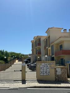 ein Zaun vor einigen Gebäuden mit geparkten Autos in der Unterkunft Jardins da guia in Albufeira