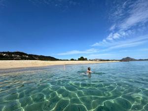 a person swimming in the water at the beach at Casa Perla Rei - 50 meters from the beach in Costa Rei