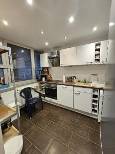 eine Küche mit weißen Schränken und einem Stuhl darin in der Unterkunft OEZ 3 Zimmer Wohnung in München