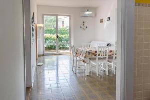 a white dining room with a table and chairs at M080 - Marcelli, residence Mare Verde trilo con giardino in Marcelli