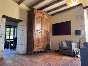 salon z dużą drewnianą szafką i krzesłem w obiekcie Gîte de L’Edelinie w mieście Nanteuil-de-Bourzac