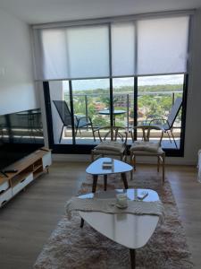 a living room with tables and chairs and a large window at Apto a estrenar en Punta in Punta del Este