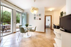 un salon avec une table, des chaises et une télévision dans l'établissement GREENMARE Mare a 100 m, 2 balconi e parcheggio gratuito, à Riccione 17 autres photos