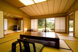 - une salle à manger avec une table, des chaises et des fenêtres dans l'établissement Hanare Kitaoka, à Itō