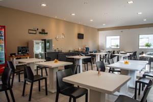 Hotel Vesubio II في فيلا جيزيل: غرفة طعام مع طاولات وكراسي بيضاء