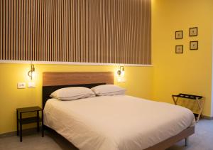 a bedroom with a large white bed with yellow walls at Lilium Suites in Rome
