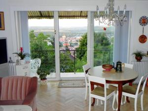 ein Esszimmer mit einem Tisch und Stühlen sowie einem großen Fenster in der Unterkunft Tulipán Panoráma Apartman in Pécs