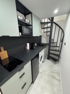 a kitchen with a black counter top and a staircase at Chic duplex Lyon avec terrasse in Vénissieux +13 photos