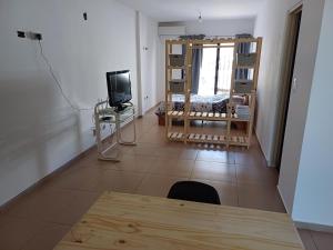 a living room with a table and a television at Complejo TuLuz - Dpto 1 dormitorio con cochera y Monoambiente, con cochera opcional en Tolosa, La Plata, in Tolosa