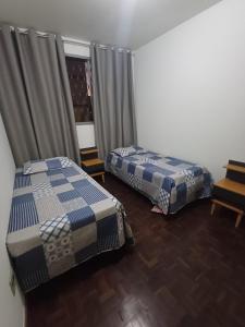 a bedroom with two beds and a window with curtains at Cê Achegue Aqui Uai in Contagem +3 photos