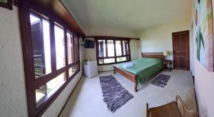 a bedroom with a green bed and some windows at Suites Vista do Baepi in Ilhabela